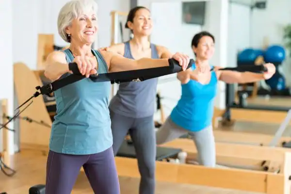 Toning Arms After 60: Empowering Womens Fitness Through Effective Weight Training 2 older woman doing weight training Dunstable and resistance in the gym to tone upper arms